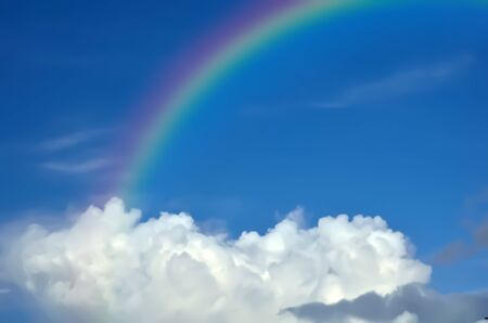 Rainbow with white cloud in sky.
