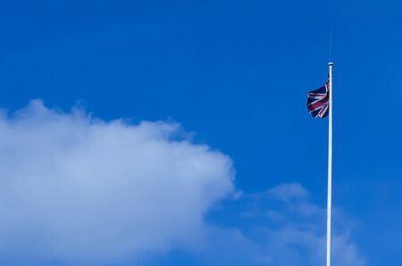 United kingdom flag is flying in blue sky.