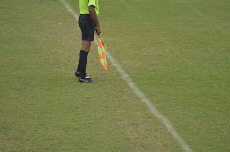 Soccer assistant referee is running with flag.