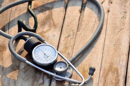 Blood pressure meter and stethoscope in wooden background.