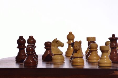 Wooden chess pieces against white for play.