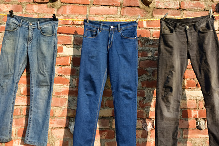 jeans hanging on a rope clothesline brick wall backgroundの写真素材