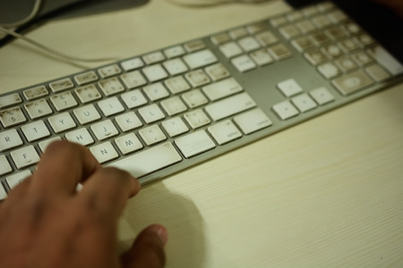 Office worker typing on a bit dirty keyboardの写真素材