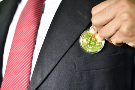 Businessman putting golden bit coin in pocketの写真素材