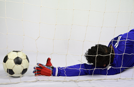 Soccer goalkeeper try to save to scoring goal against gray backgroundの写真素材