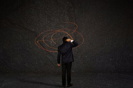 Young businessman standing and thinking about exit from complex labyrinth