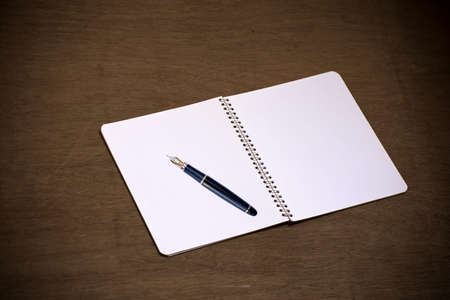 An empty blank white page of a notepad, placed over old wooden background.