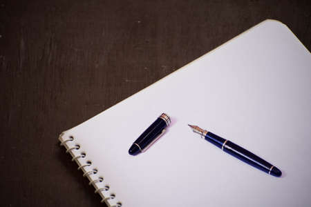 An empty blank white page of a notepad, placed over old wooden background.