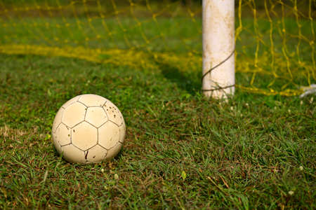 Soccer ball lying on the green grass beside the soccer goalの写真素材