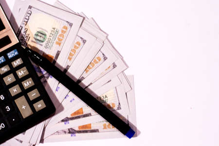 Counting US paper currency one hundred dollar in a calculator on isolated white backgroundの写真素材
