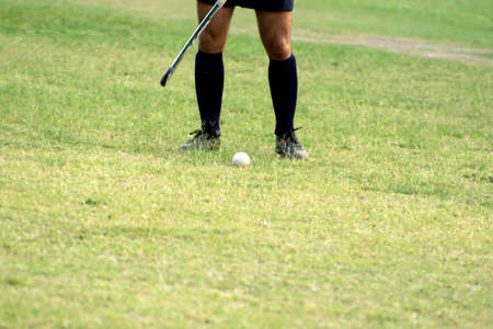 Hockey player standing beside ball to hit hockey ballの写真素材