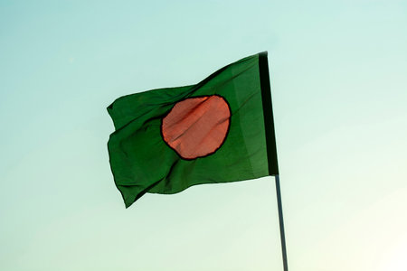 Bangladesh flag is flaying in isolated blue sky.