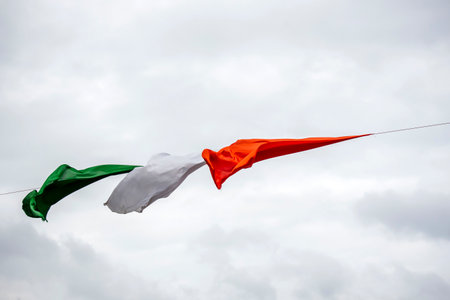 White and red flags flying in the wind against a cloudy sky.の写真素材