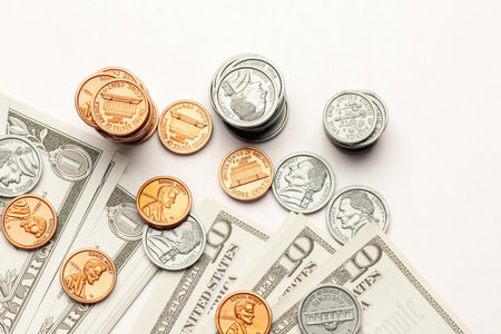 US coin and paper currency ascending like a bar graph isolated on white tableの写真素材