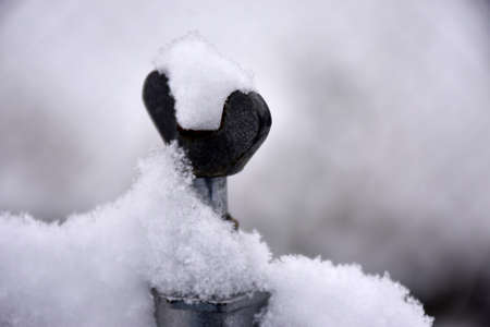 Close-up of a metal handle on a fence covered with snowの写真素材