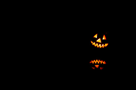 Halloween pumpkins smile and scary eyes for party night. Close up view of scary Halloween old jack-o-lantern with eyes glowing inside at black background.の写真素材