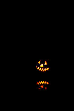 Halloween pumpkins smile and scary eyes for party night. Close up view of scary Halloween old jack-o-lantern with eyes glowing inside at black background.の写真素材