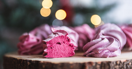 Close up of homemade cut pink zephyr or marshmallow in powdered sugar on wooden with abstract bokeh background. Black currant, blueberry marshmallows. Christmas or New Year composition. Christmas card.の写真素材