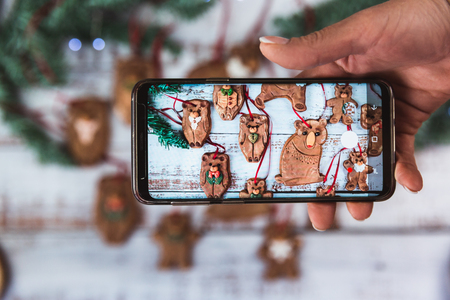 Women take photo on phone homemade Christmas gingerbread bear family cookies with sugar frosting on...