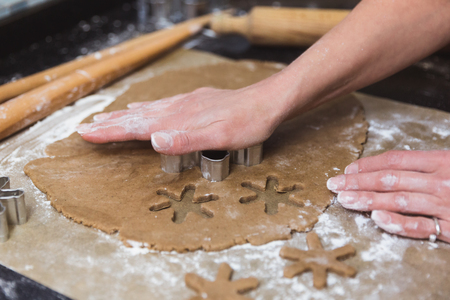 Woman makes christmas gingerbread cookies on black and red backgroundの写真素材
