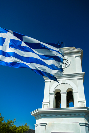 Clock Tower with a developing flag of Greece on the island of Poros in Greece, Europeの写真素材