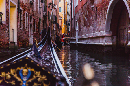 Traditional gondola on narrow canal on sunset in Venice, Italyの写真素材