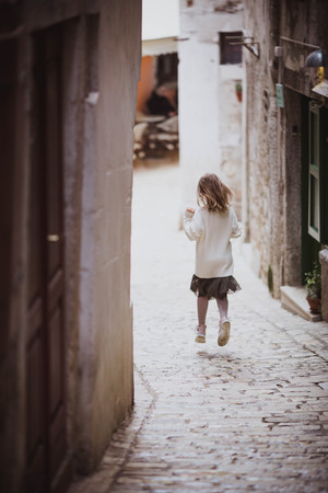 Adorable little girl in trend clothes in old town in sunny spring day. Rovinj, Croatiaの写真素材