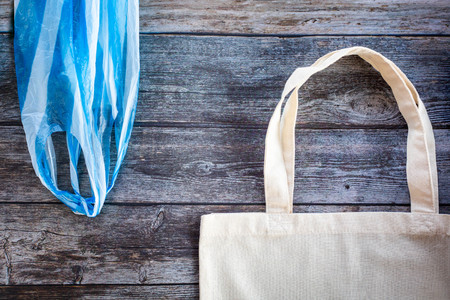 Eco Shopping Bag against a plastic bag on wooden background, Flat Lay, Top View. Save planet earth