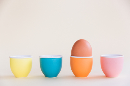 One brown egg standing on egg cup on pastel background, copy space. Easter minimal concept. Close-upの写真素材