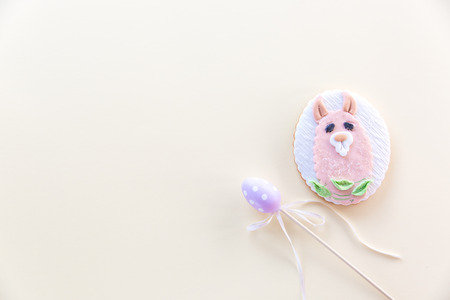 Handmade Llama shaped cookie with pastel color toy egg on a stick on a pastel background. Easter minimal concept. Flat-layの写真素材
