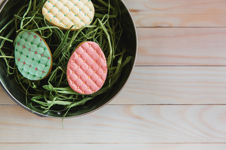 Colorful easter handmade cookies eggs in nest on light wooden background. Flat lay, top viewの写真素材