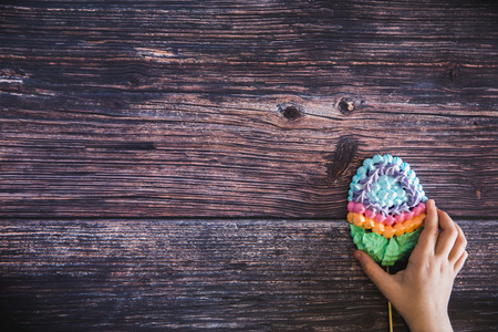 Kids hand taking a colorful sweet homemade meringues in the form of eggs on wooden background. Flat lay. Top view. Many sweet zephyrs. Trendy top view dessert image.の写真素材