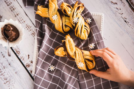 Kids hand taking delicious Palmiers with chocolate on wooden background. Easter concept, bunnyの写真素材