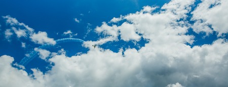 Single one sport plane of aerobatic team vapour trails in blue sky. Plane white vapour trails tracks...
