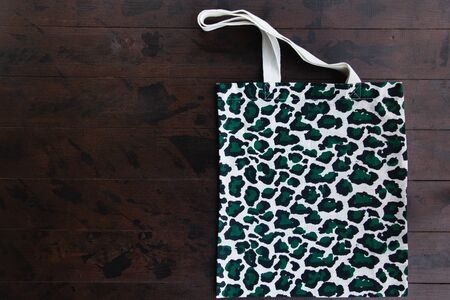 Eco Shopping Bag in trendy leopard pattern print on brown wooden background, Top View, Flat Layの写真素材