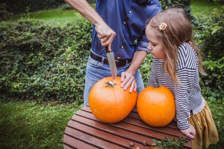 Happy halloween. Father and daughter carving pumpkin for Halloween outside. Close-upの写真素材