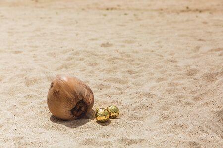 Christmas gold balls in the sand near coconut