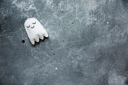 Flat lay Halloween background with decorative ghost on a grey backdrop. Copy space for text