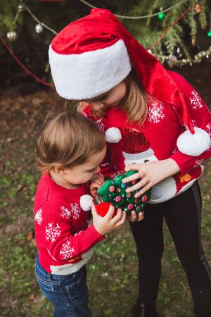 Two sisters open presents boxs near Christmas tree outdoor in the yard of the house.の写真素材
