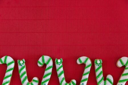 Hand painted Christmas gingerbread green and white candy cane and snowflakes on a beautiful red background. Card concept. Top view. Flat lay.の写真素材