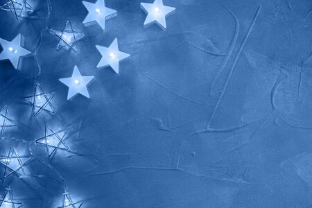 Christmas decorative garlands stars and candles glowing a light on texture background toned in blue color. Flat layの写真素材