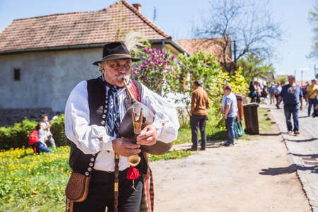 HOLLOKO, HUNGARY - April 12, 2019: Easter festival in the folklore village of Holloko in Hungary. A villager plays a national musical instrumentのeditorial素材