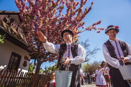 HOLLOKO, HUNGARY - April 12, 2019: Easter festival in the folklore village of Holloko in Hungary. Guys sprinkle water on girlsのeditorial素材