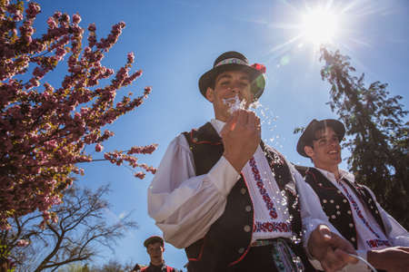HOLLOKO, HUNGARY - April 12, 2019: Easter festival in the folklore village of Holloko in Hungary. Guys sprinkle water on girlsのeditorial素材