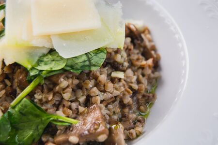 Close-up fresh buckwheat risotto with mushrooms on white plate. Delicious culinary vegan eating. Vegetarian concept.の写真素材