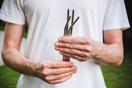 Man in white t-shirt holding a reusable steel drinking straw. Eco lifestyle and zero waste concept. Plastic freeの写真素材