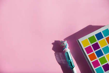 Colored notebook for notes, funny unicorn pen on pink background. Flat lay. Top view. Copy spaceの写真素材