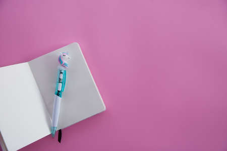 Pink notebook for notes, funny unicorn pen on pink background. Flat lay. Top view. Copy spaceの写真素材