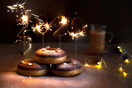 Donuts with christmas decoration with an igniting 2020 Shaped Sparkler.の写真素材