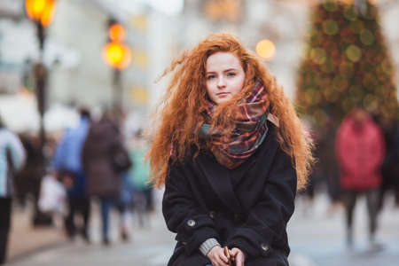 Red hair girl enjoying European Christmas Market. Blurred Lights on Christmas tree on backgroundの写真素材